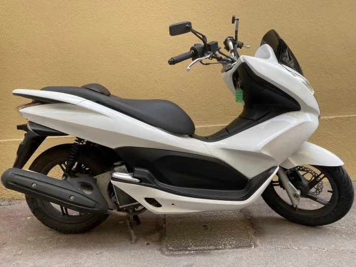 Scooter gris clair garé devant un portail