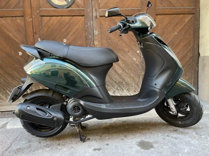 Scooter vert olive stationné en extérieur